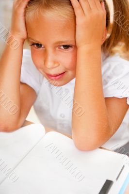 Image of smart child reading interesting book in classroom