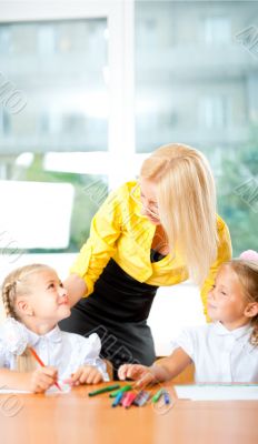 Young pretty teacher helping to her students to make exercise in