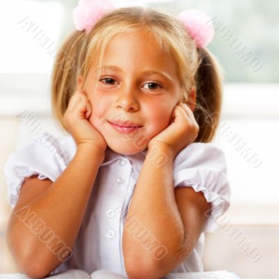 Image of smart child reading interesting book in classroom