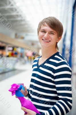 Portrait of young man inside shopping mall standing relaxed and 