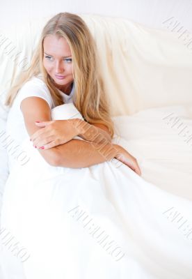 Young blond woman enjoying a sunny morning in bed