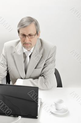 Portrait of an older businessman with a computer and a cup.