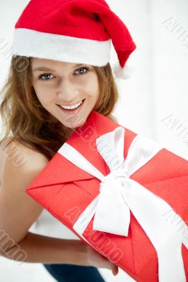 Young happy girl in Christmas hat. Standing indoors and holding 