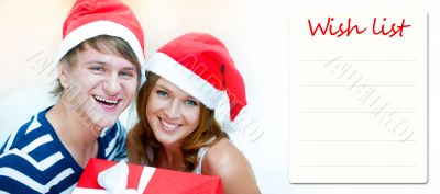 Young happy couple in Christmas hats standing together and holdi