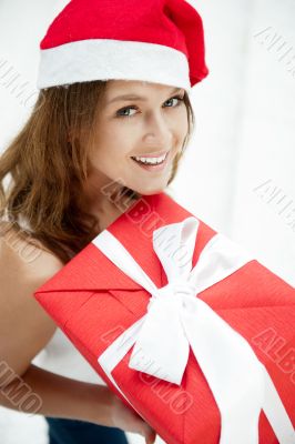 Young happy girl in Christmas hat. Standing indoors and holding 
