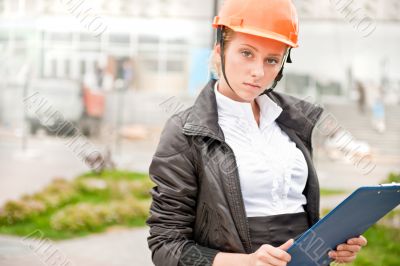 Young architect-woman wearing a protective helmet standing on th