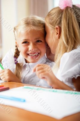 Two little girls gossip in classroom