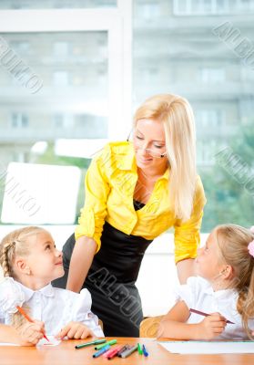 Young pretty teacher helping to her students to make exercise in