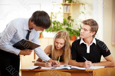 Teacher helping students in school classroom. Horizontally frame