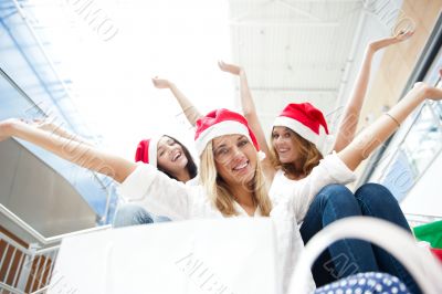 Group of three beautiful girls sitting on stairs at shopping mal