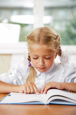 Portrait of a young girl in school at the desk.