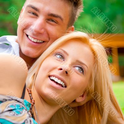 Portrait of beautiful young couple sitting on ground in park rel