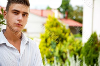 Satisfied smiling businessman standing in the green outdoors.