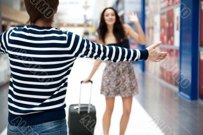 Young man meeting his girlfriend with opened arms at airport arr