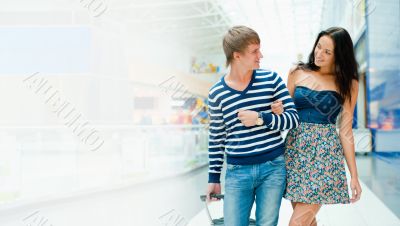Portrait of young couple walking together at airport hall with t