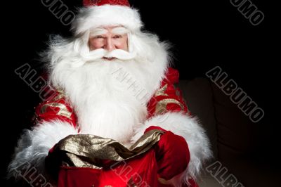 Santa sitting at the Christmas room and looking into the sack