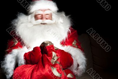 Santa sitting at the Christmas room and looking into the sack