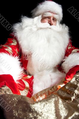 Santa sitting at the Christmas room and looking into the sack