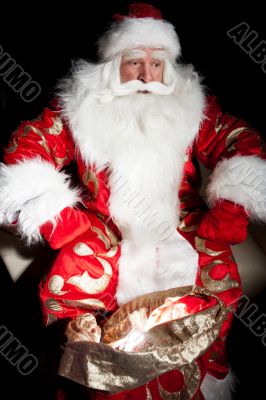 Santa sitting at the Christmas room and looking into the sack