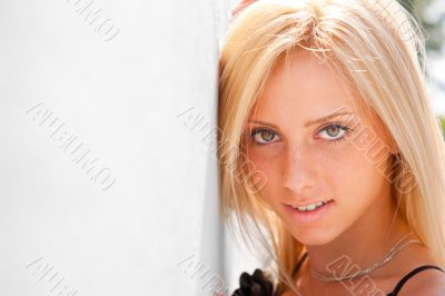 Portrait of pretty young woman standing outdoors near white wall