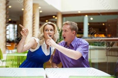 Young debating or talking couple inside mall sitting near the ta