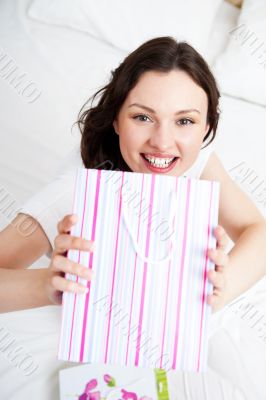 Portrait of young beautiful awake woman with gifts on bed at bed