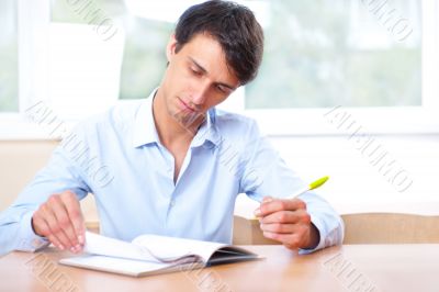 Businessman sitting indoors and writing plan in his diary