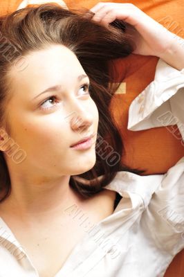 Closeup portrait of young pretty girl laying on her bed