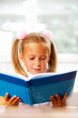 Image of smart child reading interesting book in classroom