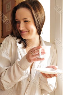 Portrait of cosy young girl standing near a window at home