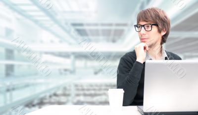 Portrait of a young business man sitting by his laptop in the of