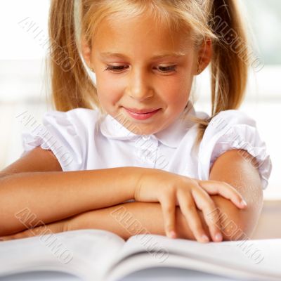 Image of smart child reading interesting book in classroom