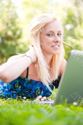 Portrait of young pretty woman resting on green grass at summe
