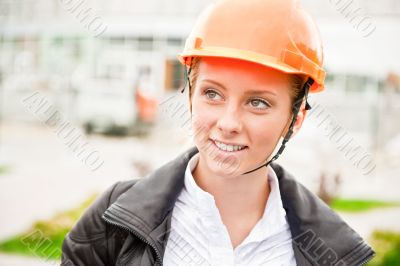 Young architect-woman wearing a protective helmet standing on th