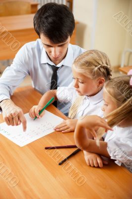 Teacher helping elementary school pupils with their tasks