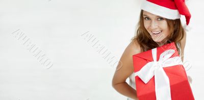 Young happy girl in Christmas hat. Standing indoors and holding 