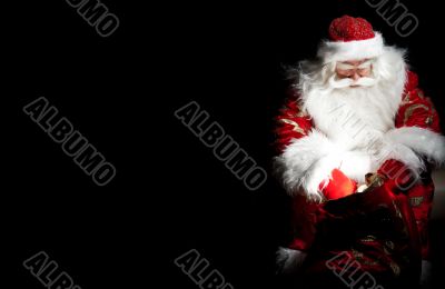 Santa sitting at the Christmas room and looking into the sack