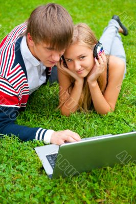 Happy young couple using laptop while lying on grass