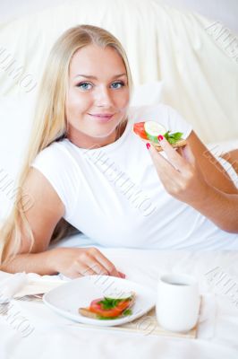 Woman having breakfast in bed. Healthy continental breakfast. Ca