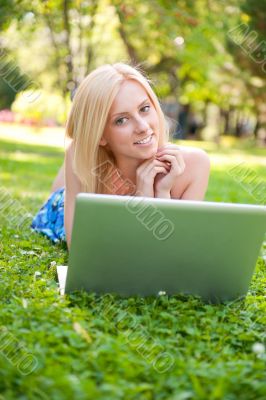 Portrait of young pretty woman resting on green grass at summe