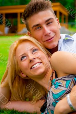 Portrait of beautiful young couple sitting on ground in park rel
