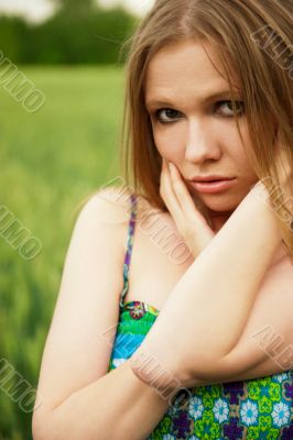 Portrait of young woman stands in a field of wheat with joy