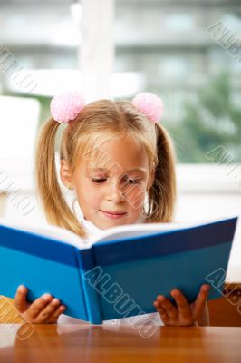 Image of smart child reading interesting book in classroom