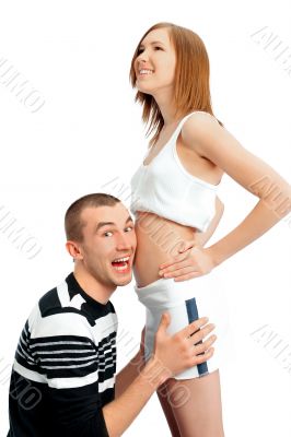 Cheerful man listening the belly of his pregnant wife