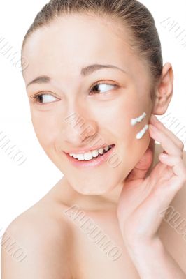 Portrait of a beautiful young woman applying cream to her face a