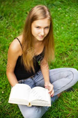 Beautiful female student outdoors with a book at campus park