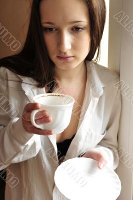Portrait of cosy young girl standing near a window at home