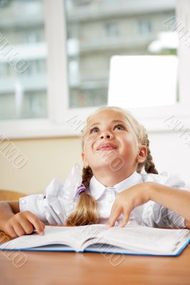 Portrait of a young girl in school at the desk.