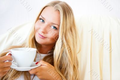 Young woman at home sipping tea or coffee from a cup