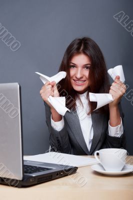Image of young businesswoman with crumbled paper sitting happy a